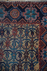 Corner of an antique Persian Afshar rug with floral lattice field and geometric navy border.
