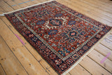 Vintage Karaja rug displaying its geometric triple medallion and rust-red floral field from an angle.
