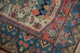 Vintage Malayer rug corner with soft pile, fuchsia blossomed planters, and blue geometric border.