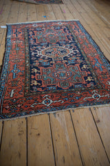 Angled view of vintage Karaja rug, geometric terracotta border, navy field, even pile wear.