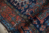 Textural detail of vintage Persian Karaja rug, showing geometric patterns in terra cotta, navy, green.