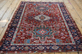 Corner of vintage Karaja rug, cherry red field with geometric motifs, navy border, mostly even wear.