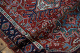 Karaja rug's cherry red field with geometric blossoms, navy border, and aged pile.