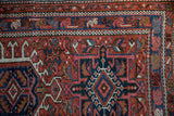 Vintage Karaja rug corner showing a brick red, navy, and blush meandering vine floral border.