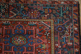 Corner of Karaja rug, cherry red field with hook and latch, intricate navy floral border.