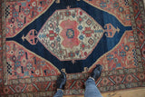 Vintage Malayer rug corner detail: navy reciprocating spandrel, red avian motifs, vine border.