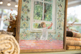 Angled view of painting's textured surface, green floral patterns, and handmade wooden frame.
