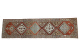 Distressed vintage Malayer rug runner with a column of geometric medallions in rust, slate blue, and ivory.
