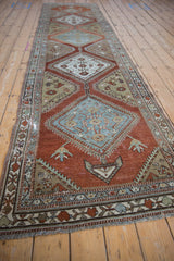 Angled view down the length of a distressed Malayer runner with geometric diamond medallions.