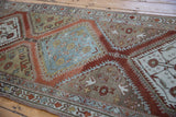 Angled view of a distressed Malayer runner showing its slate blue medallion and abrashed rust ground.