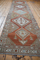 Angled perspective view down the length of a vintage distressed Malayer rug runner.