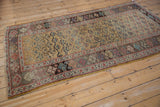 Antique Kurdish Bijar rug corner detail: ochre henna motif field, geometric border, visible wear.