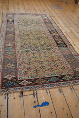 Fringed corner of Antique Kurdish Bijar rug, ochre field with henna motif, dark geometric border.