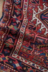 Vintage Karaja rug fold, showcasing cherry red, navy, sky blue geometric motifs and textured pile.
