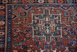 The floral border and geometric medallion corner of a vintage Persian Karaja rug in brick red and sapphire blue.