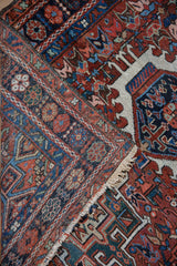 Folded corner of a vintage Karaja rug showing its hand-knotted texture, tattered fringe, and geometric borders.