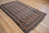 Corner detail of vintage Kurdish rug showcasing intricate arabesque boteh patterns in navy, blush, and brown.