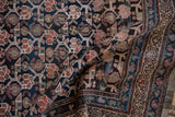 Folded vintage Kurdish rug: navy, blush, beige geometric border and woven side selvage.