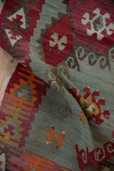 Close-up of folded Turkish Kilim, showing geometric plant motifs and abrashes in seafoam green.