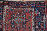 Close view of a vintage Karaja rug's corner showing the navy border and geometric brick red field.