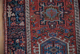 Wide navy main border with geometric flowers and intact side cord of a vintage Karaja rug.