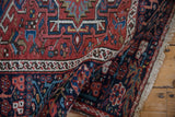 Folded corner of a vintage Karaja rug showing its low-pile texture and short ivory fringe.