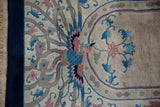 Detail of the hand-knotted phoenix motif in blush and blue against the rug's cobalt border.