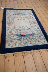 Angled perspective of a vintage Art Deco rug with its full pictorial phoenix pattern and cobalt blue border.