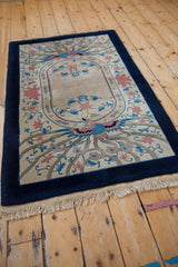 Angled view of the vintage rug's phoenix pattern, cobalt blue border, and ivory fringe.