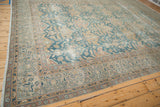 Distressed Agra carpet corner detail, showing intricate dusty ocean blue and mauve blossoms with wear.