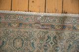 Distressed Agra carpet fringe and border, showing worn pile, antique ivory field, and faded dusty blue palmettes.