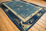 Antique Peking carpet corner showing dark blue border, beige motifs, and aged edge.