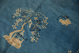 Detail of antique Peking carpet showing tree, bird, and floral sprays in blue, beige, ivory.