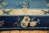 Antique Peking carpet's end with indigo, sky blue, and ivory bird and floral motifs, exposing foundation.