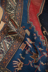 Curled antique Malayer rug: unusually fine weave, navy blue primitive motifs, and cherry red foundation.