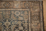 Distressed vintage Malayer rug corner with faded teal Herati and beige palmette border.