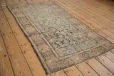 Malayer rug's worn palmette border, faded teal Herati field, and side tatter.
