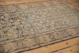 Faded teal Herati pattern field and geometric palmette border detail on a distressed Malayer rug.