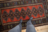 A standing perspective of an antique Kurdish rug, showing the scale of its gem-toned geometric medallions.