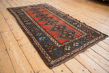 Angled profile of an antique Kurdish rug, highlighting its rich texture and geometric medallions.