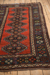 A detail of the geometric diamond medallions and multi-layered border on an antique Kurdish rug.