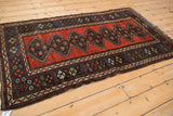 An angled perspective of a collector's antique Kurdish rug with a bold geometric design in rich gem-tones.
