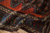 Folded view of an antique Kurdish rug revealing the low pile texture, even wear, and rich gem-toned colors.