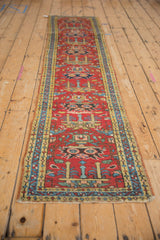 Vintage Heriz runner's cherry red field with germinating plant motifs, dusty gold, and blue borders.