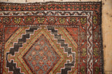 Vintage Hamadan rug corner: stepped medallion, geometric border in brick red, charcoal, gold.