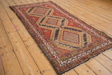 Hamadan rug detail showing brick red border, white and gold geometric patterns, and stepped medallion.