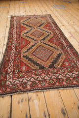 Vintage Hamadan rug close-up: stepped medallion, herdsmen motifs in brick red, charcoal, and gold.