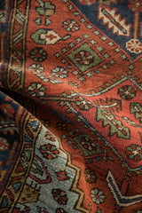 Textured hand-knotted pile of a folded vintage Heriz rug, featuring serrated leaves and blue geometric spandrel.