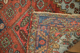 Worn brick red Heriz rug pile showing exposed blue hand-knotted foundation.