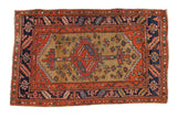 Antique Heriz rug showing a serrated hexagonal medallion on a gold ochre field with navy and brick red borders.